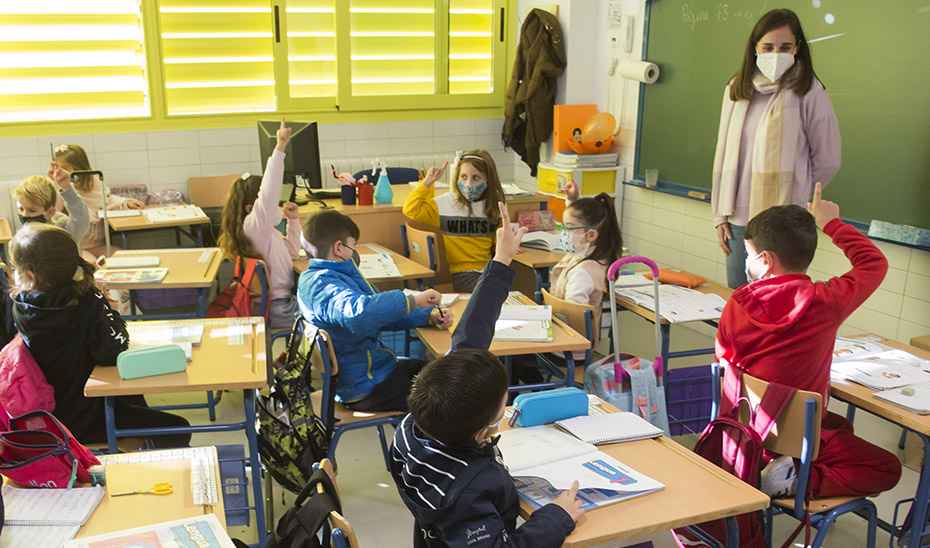Una profesora y sus alumnos, con mascarilla, en clase.