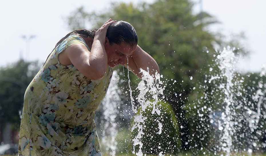 Una mujer se refresca en una fuente.