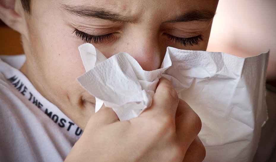 Un niño utiliza un pañuelo de un solo uso tras estornudar.