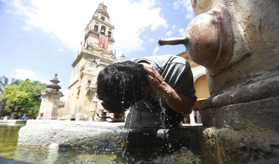 Una persona se refresca bajo una fuente en Córdoba.
