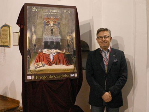 Agustín Serrano junto al cartel de la Semana Santa prieguense 2014, del que es su autor. (Foto. R. Cobo)